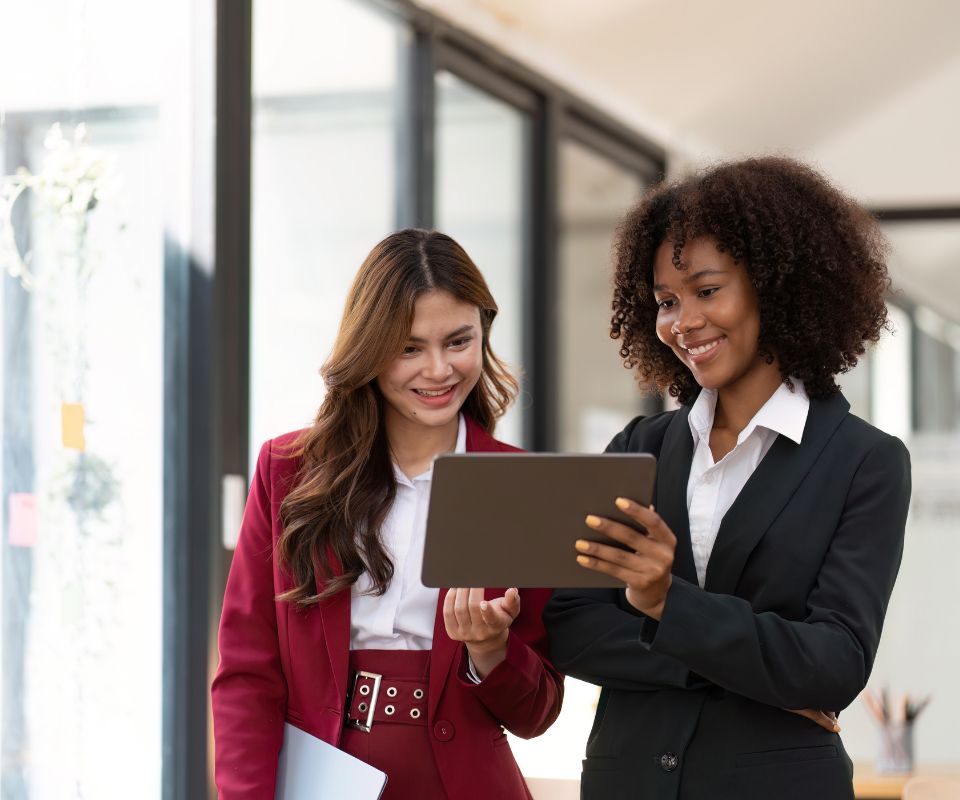 Duas mulheres em escritório financeiro analisando automação de pagamentos com API em um tablet